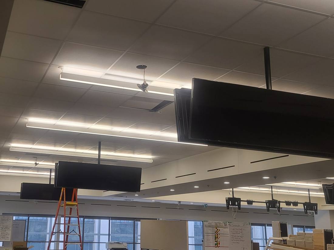 Multiple ceiling-mounted displays being installed across an open office
