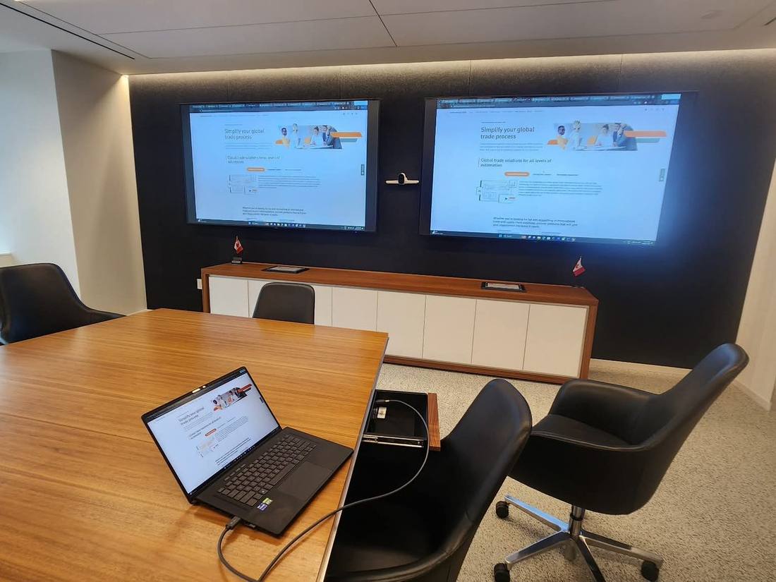 Executive boardroom with dual displays mirroring a laptop