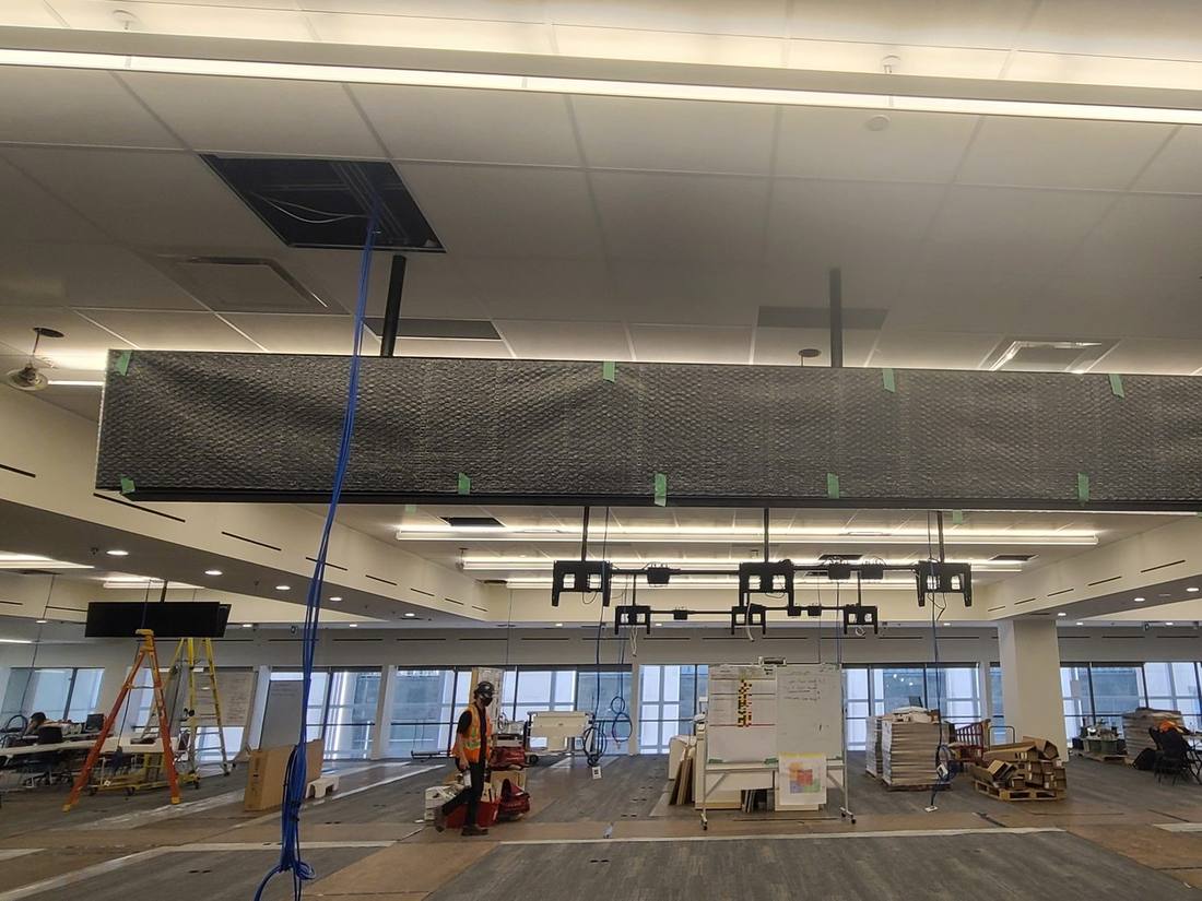 Open office floor under construction with a mesh-wrapped ceiling display