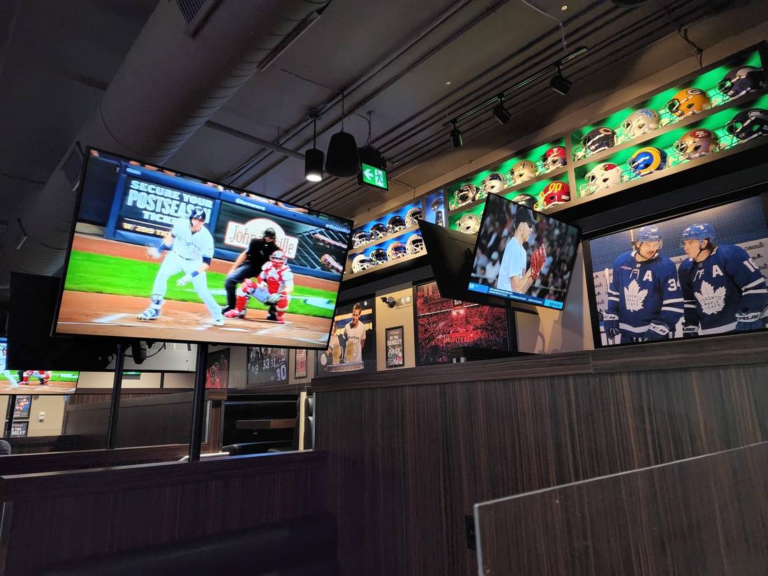 Sports bar with synced multi-display TVs and a lit helmet display shelf