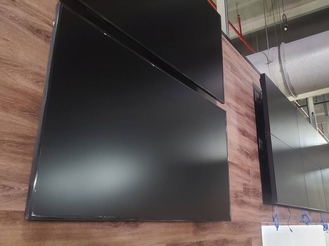 Two displays mounted on a wood-panel wall during construction
