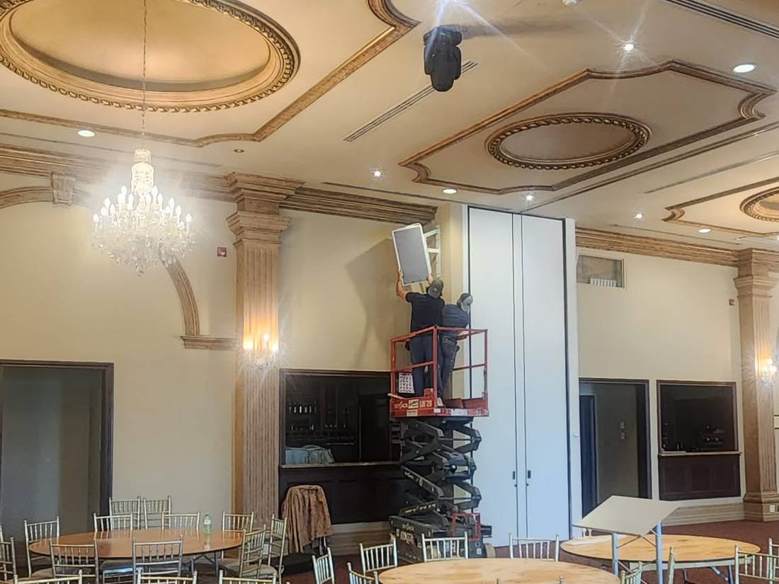 Crew on a scissor lift installing a display in a gilded ballroom
