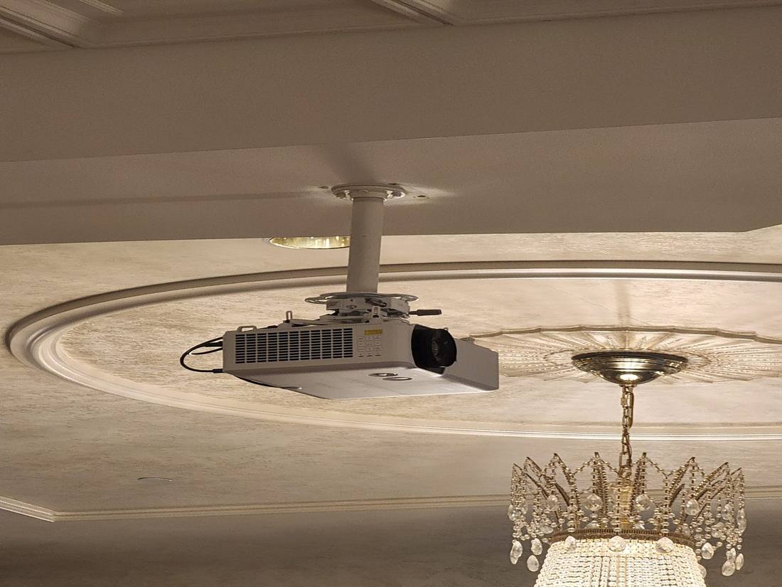 Ceiling-mounted projector recessed near a decorative medallion