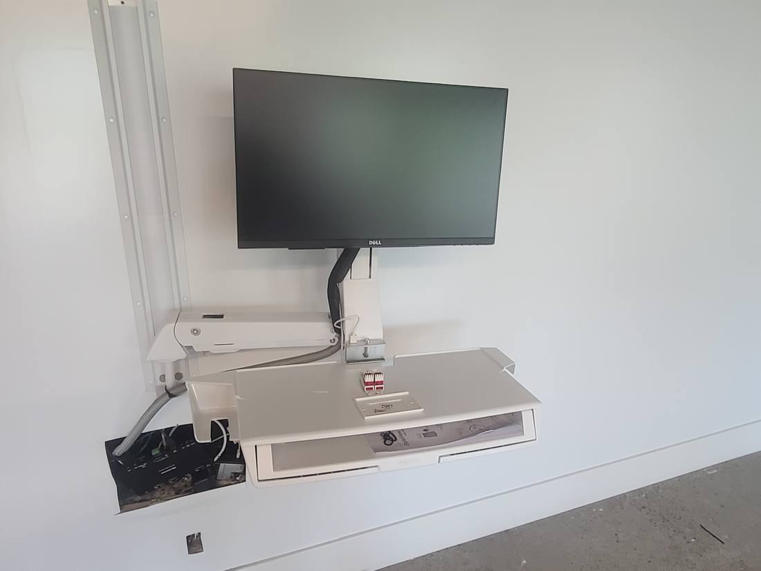 Close-up of a wall-mounted monitor arm and keyboard tray