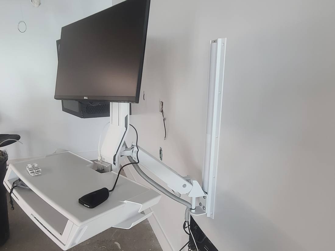 Wall-mounted clinical workstation with monitor arm and keyboard tray