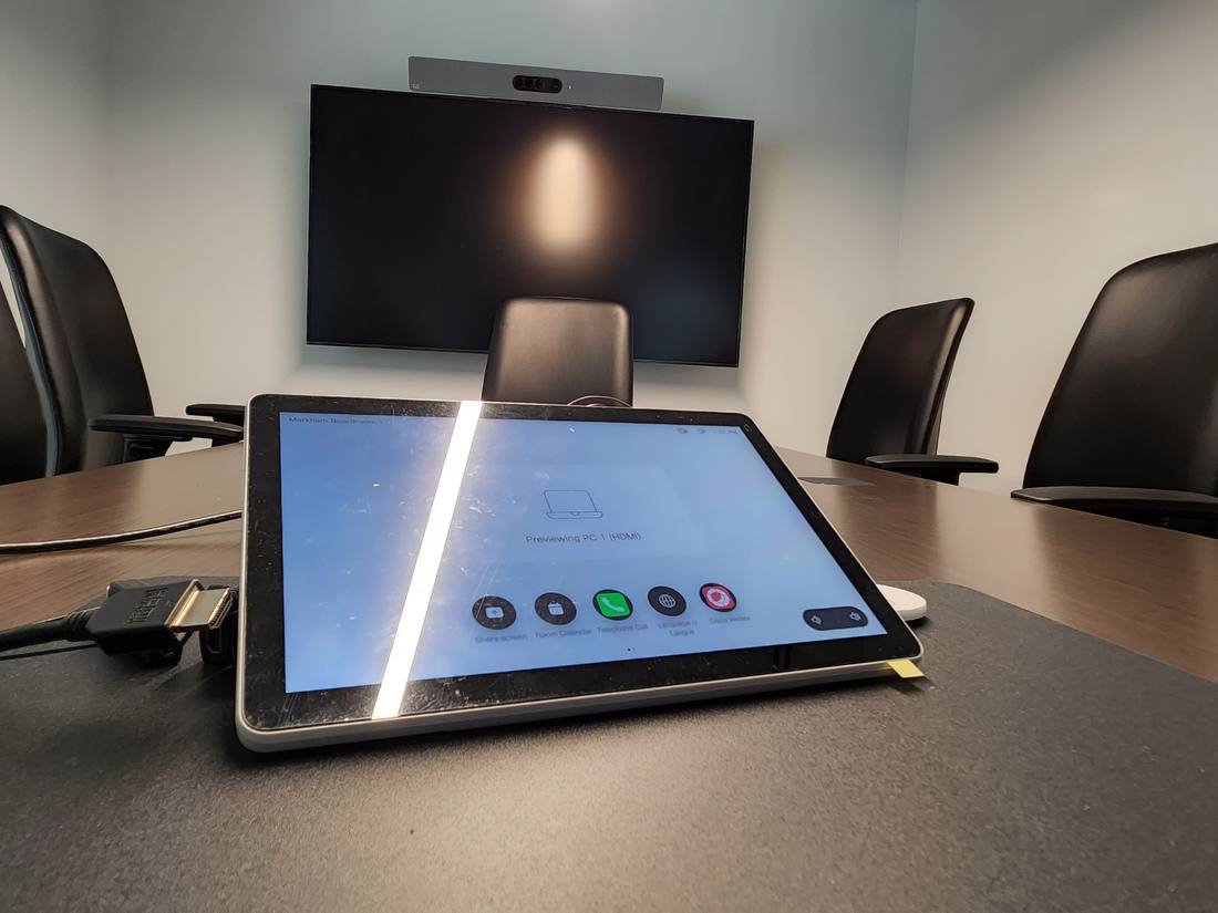 Touch panel room controller on a boardroom table with a display behind