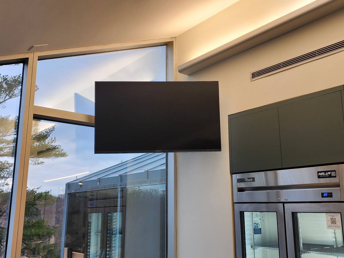 Wall-mounted television beside a glass curtain wall in a break room