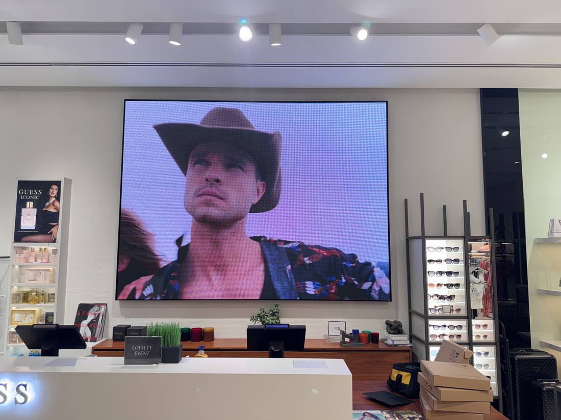 Framed LED video wall behind a fashion retailer's checkout counter