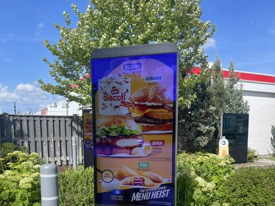 Drive-thru digital menu board framed by landscaping